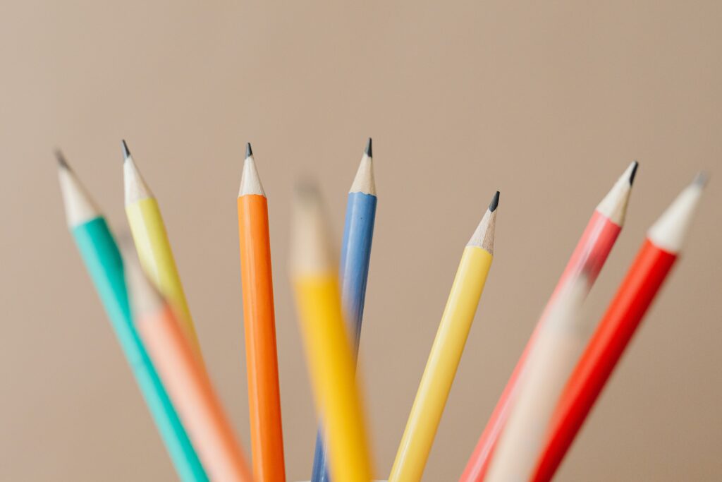 Vibrant close-up of sharpened colored pencils against a beige background, ideal for creative concepts.